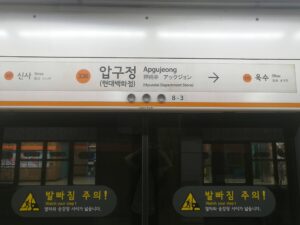 3号線狎鷗亭駅ホーム。中央336狎鷗亭（現代百貨店）、左337新沙、右矢印335玉水。地下駅の白い照明。