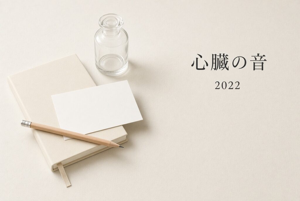 象牙色の紙の上に、ノートとガラス瓶。右に「心臓の音 2022」。